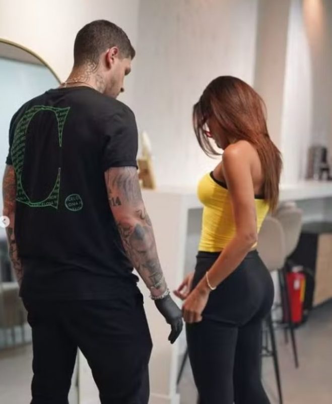 na imagem aparece Anitta na grécia com o tatuador Ivan Casabó escolhendo desenho da tatuagem