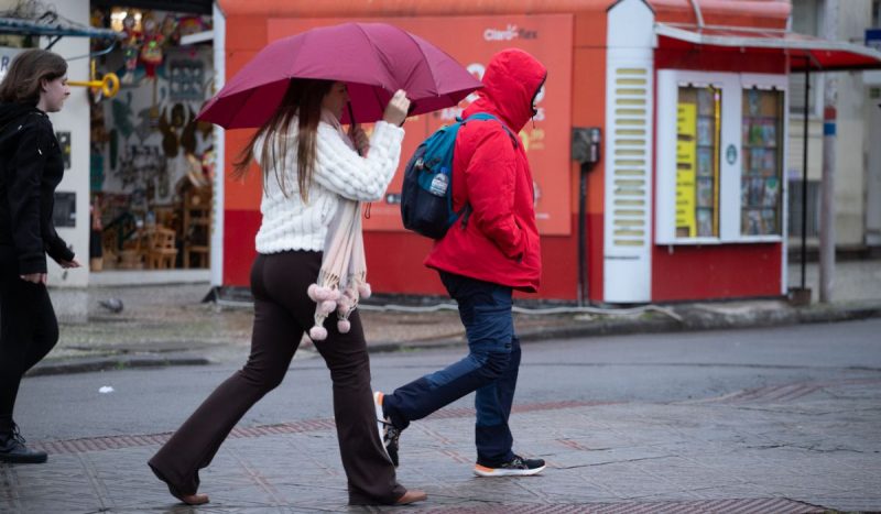 Mulher andando com guarda-chuva e homem de casaco vermelho