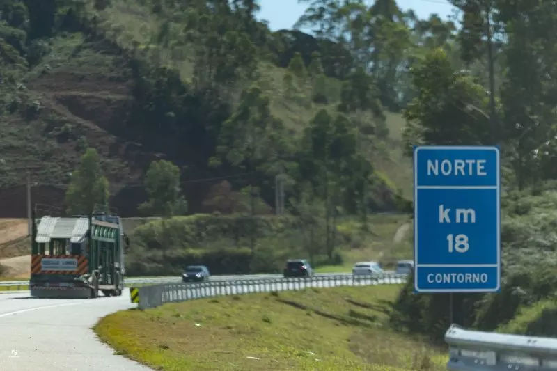 Imagem de carros no contorno viário com placa do km 18 sentido Norte