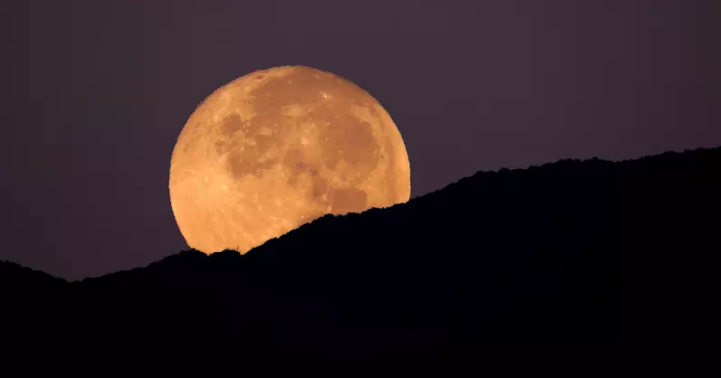 Lua cheia por trás de montanhas