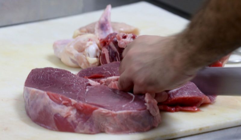 Homem cortando uma carne bovina