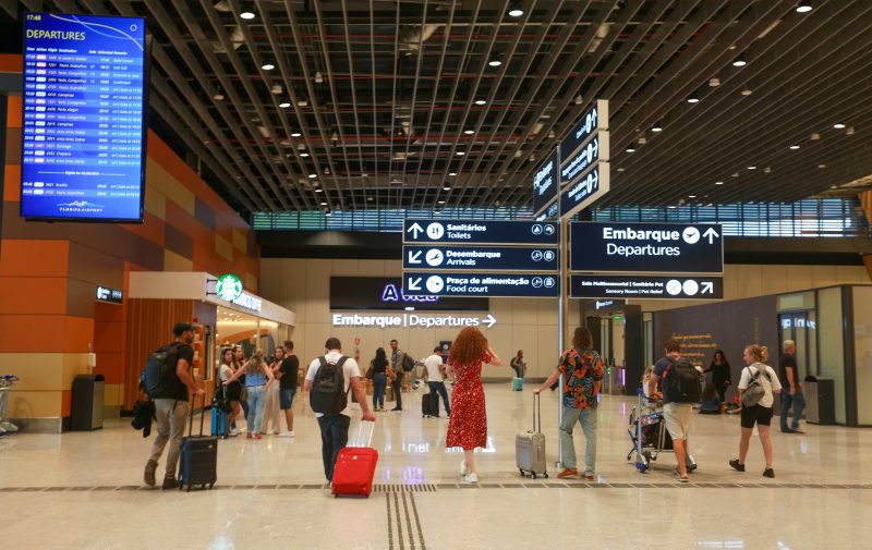 Pessoas andando no aeroporto com malas nas mãos