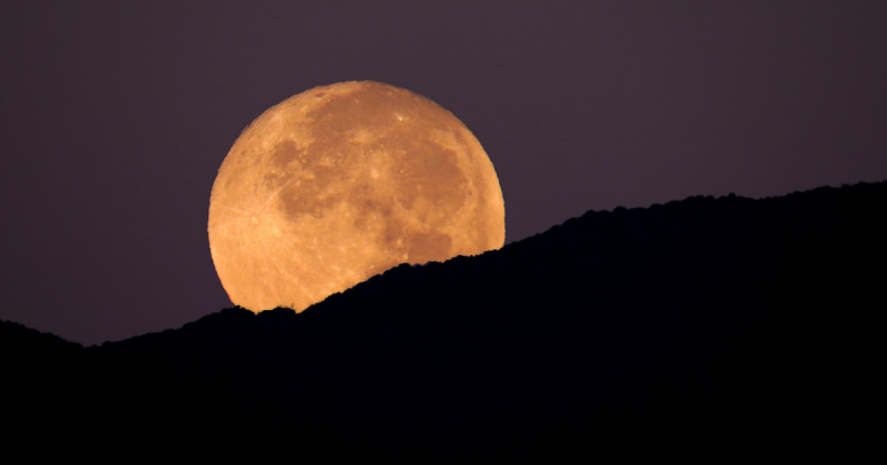 Lua por trás de paisagem escura e montanhas